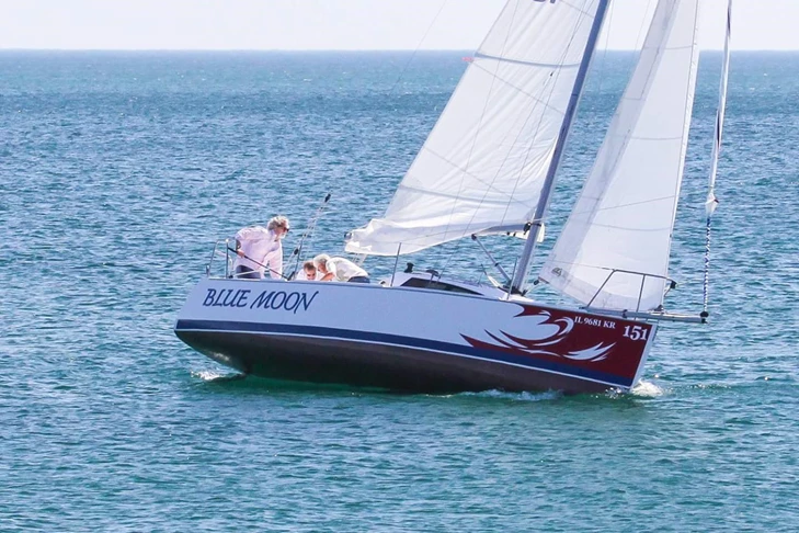 Sailboat underway on Lake Michigan with name on sides and red wave wrap graphic on bow