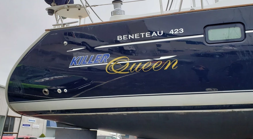 Lettering on sides of sailboat in white, blue and metallic gold
